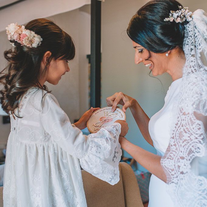 Novia mostrando a su hija un porta alianzas de bastidor bordado a mano de Arorua Bodas para el momento del altar.