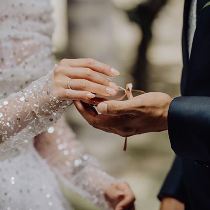 Pareja de novios intercambiando alianzas con porta alianzas de metacrilato oro rosa personalizado de Arorua Bodas.