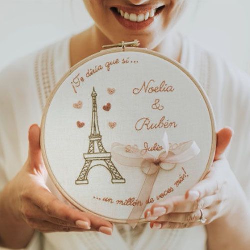 Novia sonriente con porta alianzas bastidor diseño Torre Eiffel entre las manos de AroruaBodas