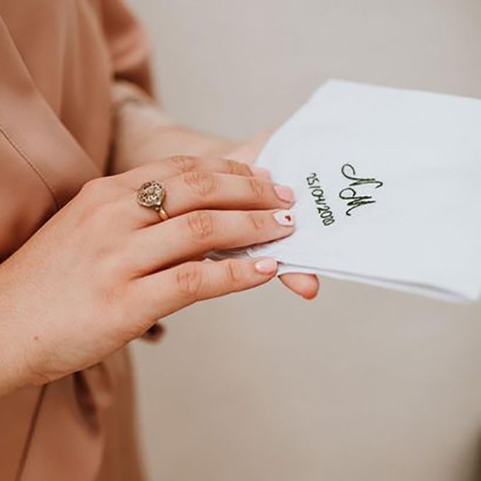 Pañuelo de novio bordado a mano con iniciales y fecha de boda, sostenido por la madrina - Arorua Bodas