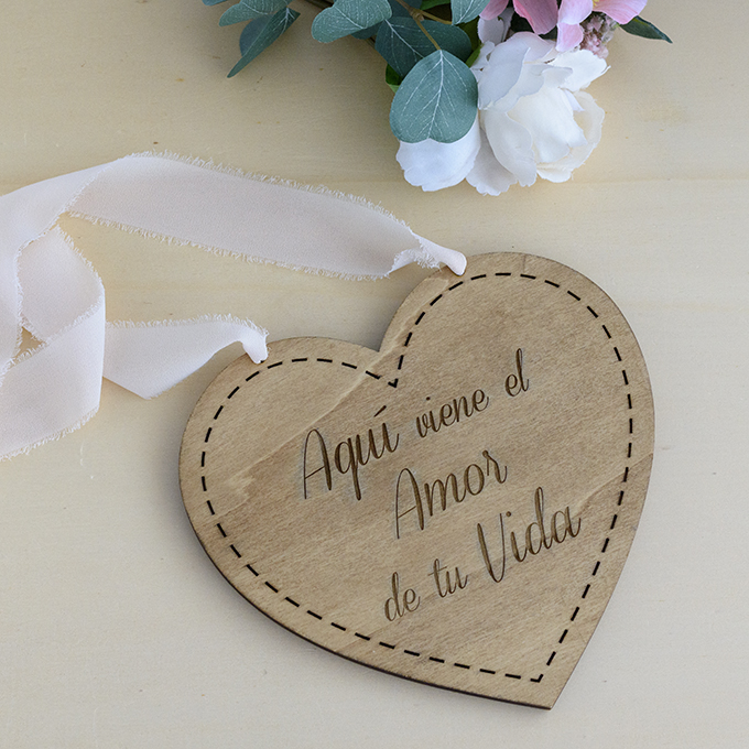 Cartel de madera para boda con forma de corazón y grabado con el texto "Aquí viene el Amor de Tu Vida" de Arorua Bodas